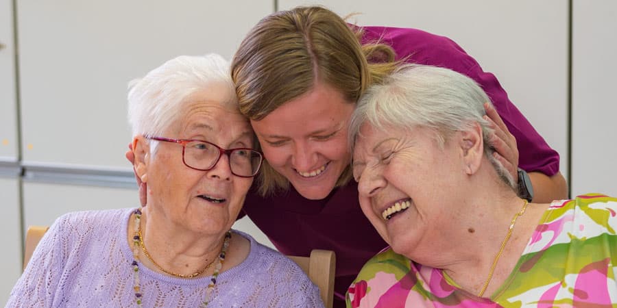 Bewohnerinnen lachen mit Pflegefachkraft